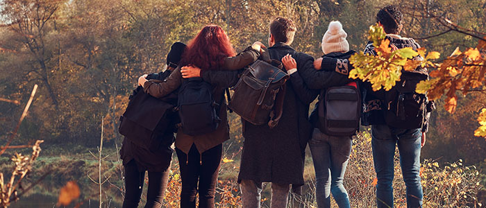 travel-hiking-adventure-concept-back-view-of-young-friends-hugging-together-and-looking-at-the-lake-in-beautiful-autumn-forest